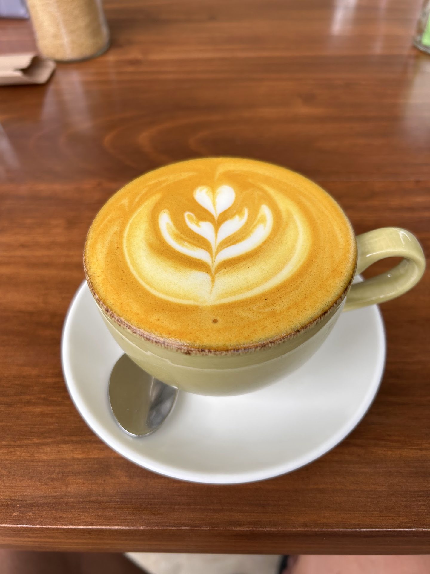 Latte con arte de espuma en una taza verde salvia