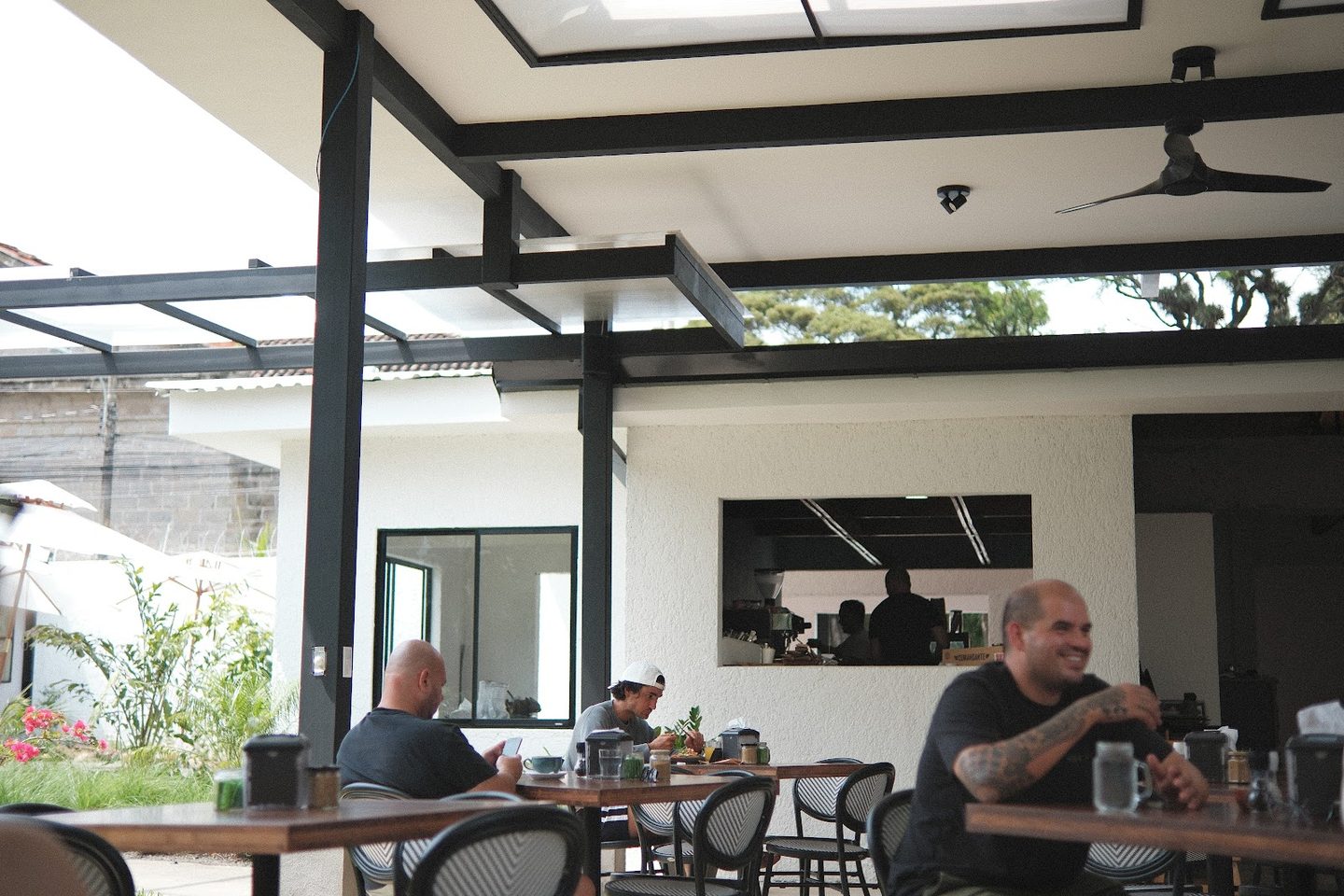 El pabellón techado con la pérgola de acero y la barra de café al fondo